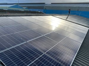 A view across a warehouse roof with solar PV panels and an InspireGreen fitter in the background.
