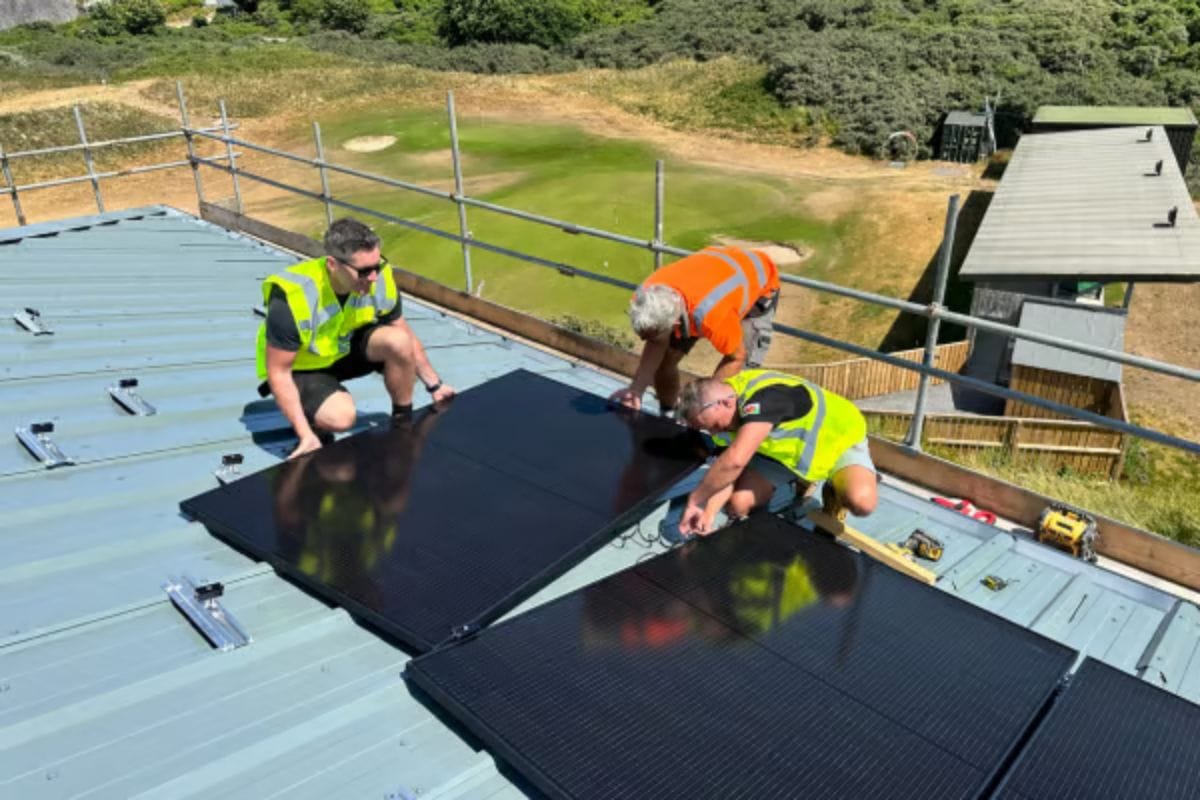 Members of the InspireGreen team working to install solar PV panels on a commercial roof.