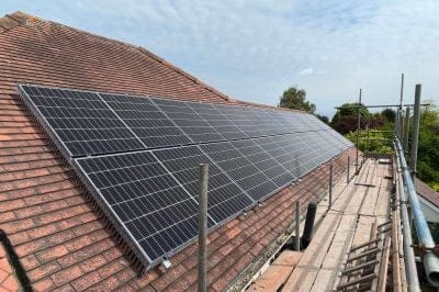Solar panels mid-installation on a residential roof with scaffolding below.