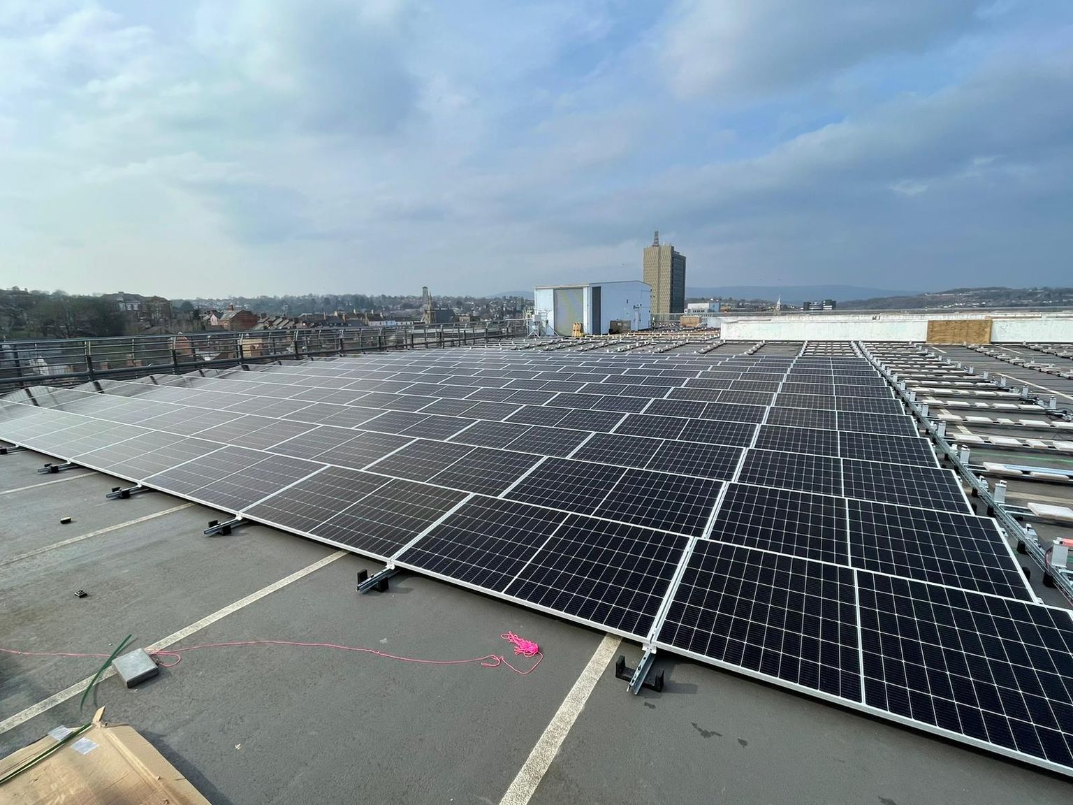 Rows of solar panels in the sun, alongside fittings yet to be installed.